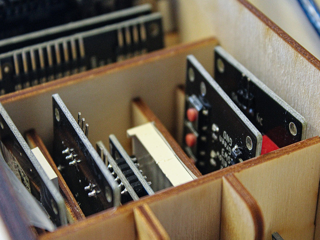 Close-up view of assorted electronic circuit boards with various components slotted into a wooden storage rack