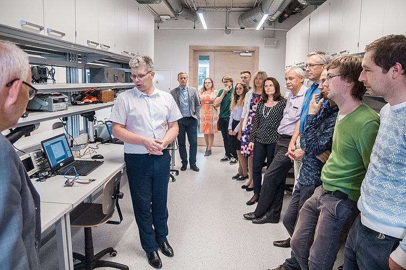 A presenter explaining technical equipment to a group of professionals in a lab environment.