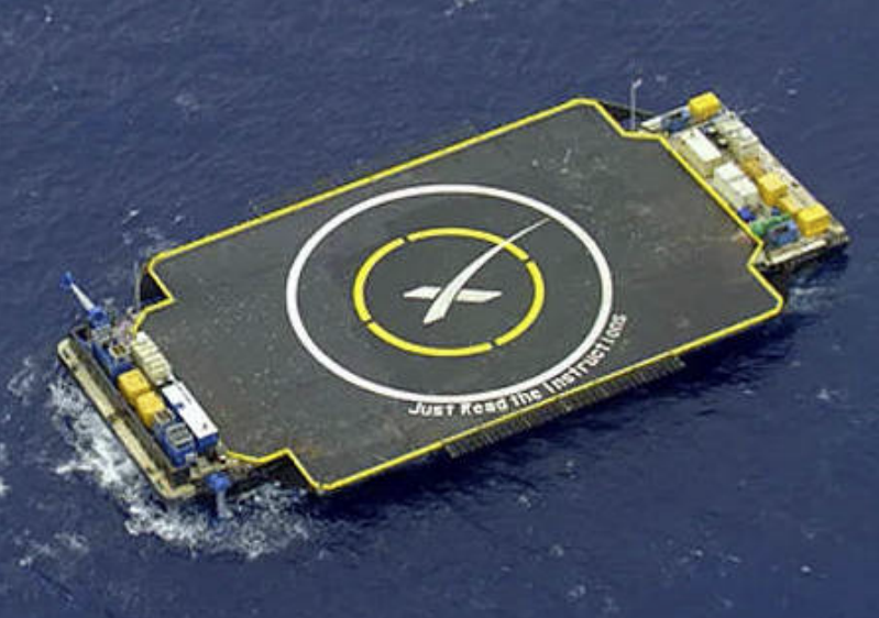 An aerial view of SpaceX's autonomous drone ship with a helipad design and the inscription 'Just Read the Instructions'.